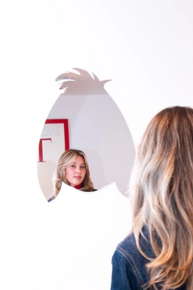 Visitor reflected in Jeff Koons' playful silhouette mirror at Moco Museum